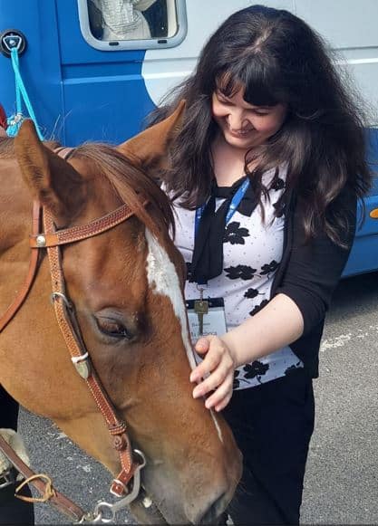 Rebeca Duriga about to put her left hand on a horse.