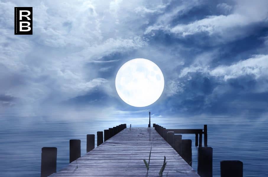 Peaceful moon over a bridge at night.