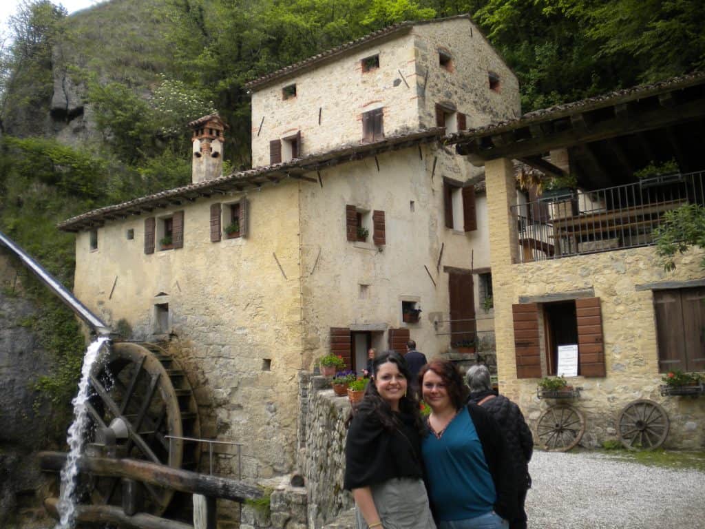 Rebeca Duriga and Ema, one of her sisters, smiling in front of a water mill.